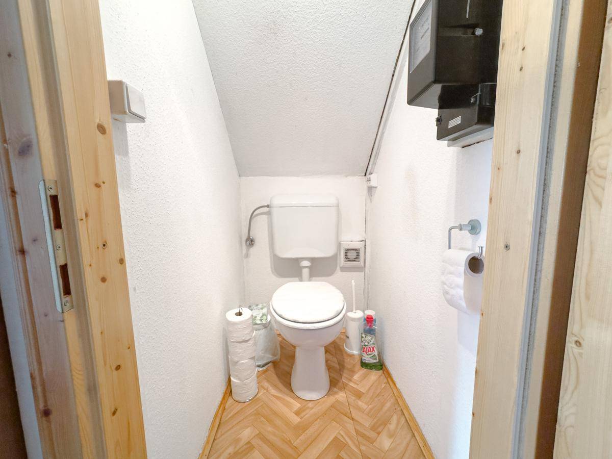 Kleines WC im Dachgeschoss mit schräger Decke und Fenster, funktional eingerichtet.