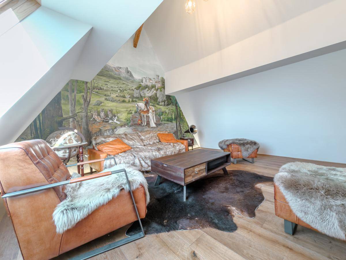 Einzigartiges Wohnzimmer im Dachgeschoss mit Wandgemälde, Holzboden und rustikalen Möbeln.