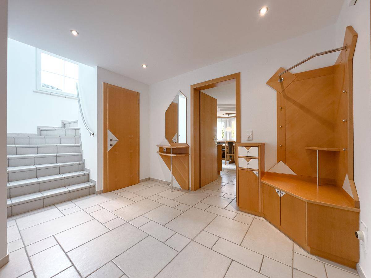 Geräumiger Flur mit Fliesenboden, Garderobe und Treppenaufgang.