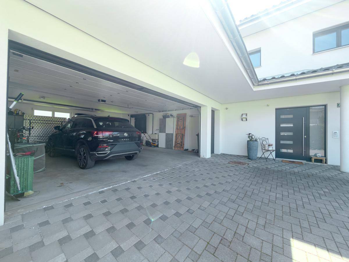 Geräumiger Carport und Garagenbereich mit Zugang zum modernen Haus.