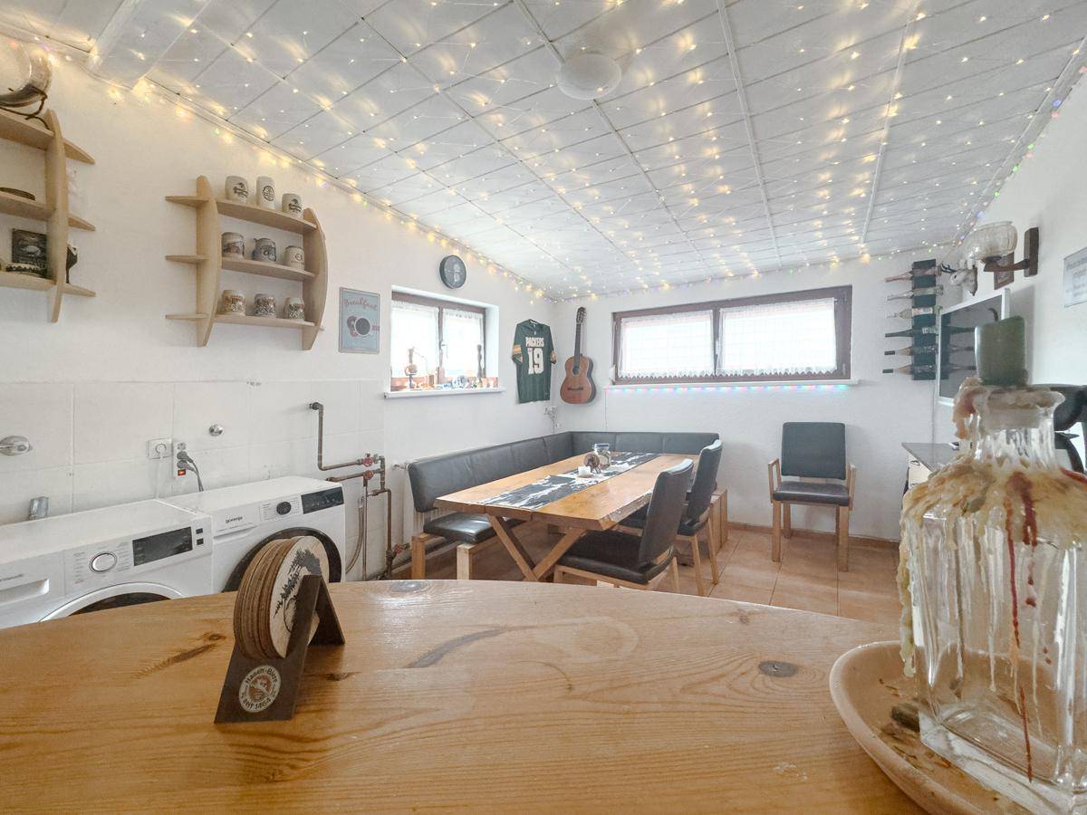 Vielseitiger Raum mit Essbereich, Waschmaschine und festlicher Lichterkette an der Decke.