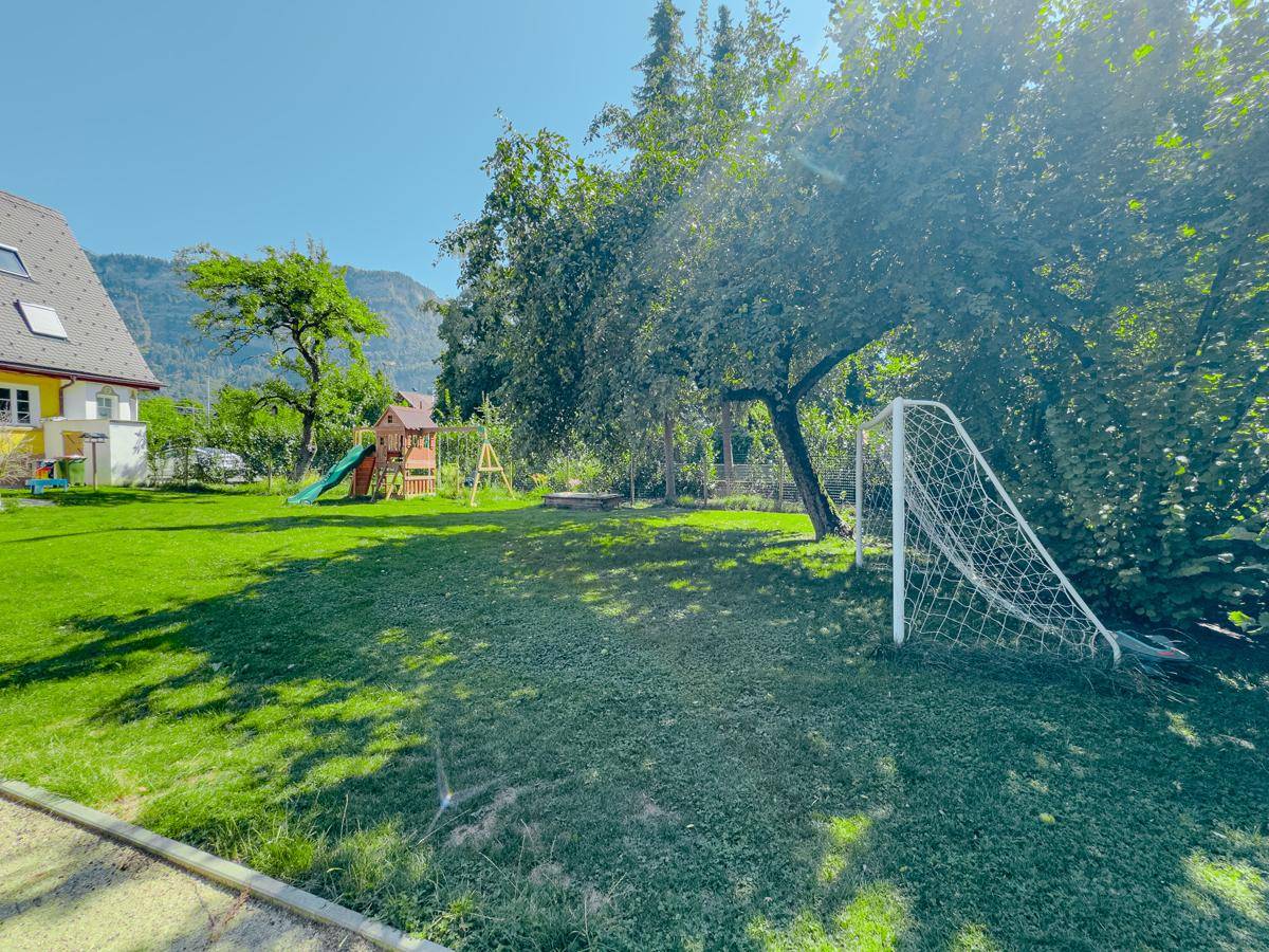 Großer Garten mit Spielplatz, Fußballtor, Rasen und Blick auf das Haus sowie die umliegende Berglandschaft.