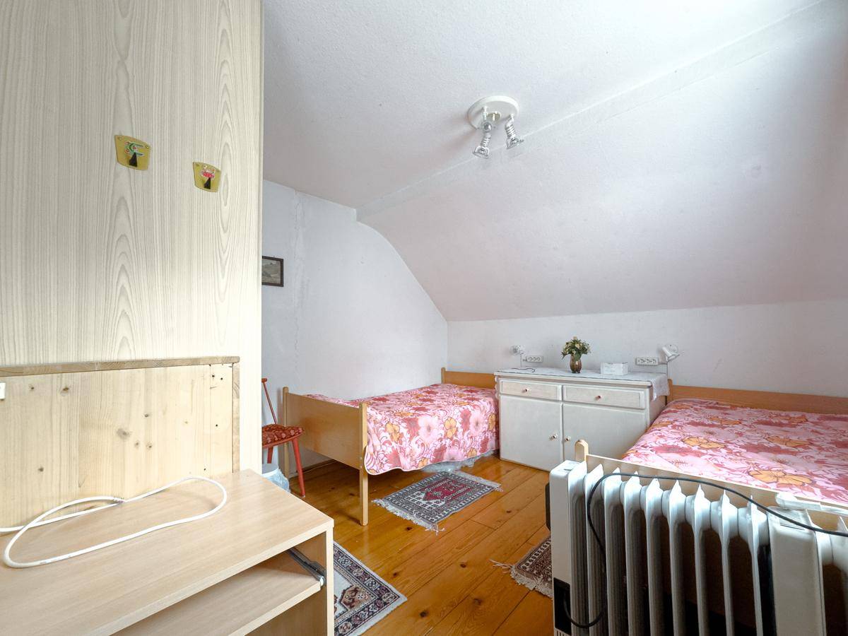Schlafzimmer im Dachgeschoss mit zwei Einzelbetten, Holzfußboden und schräger Decke.