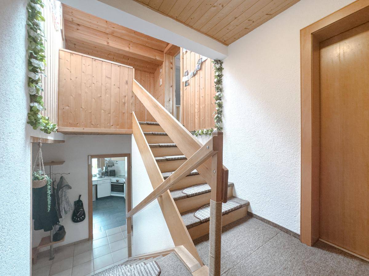 Helle Holztreppe verbindet die verschiedenen Ebenen des Hauses.
