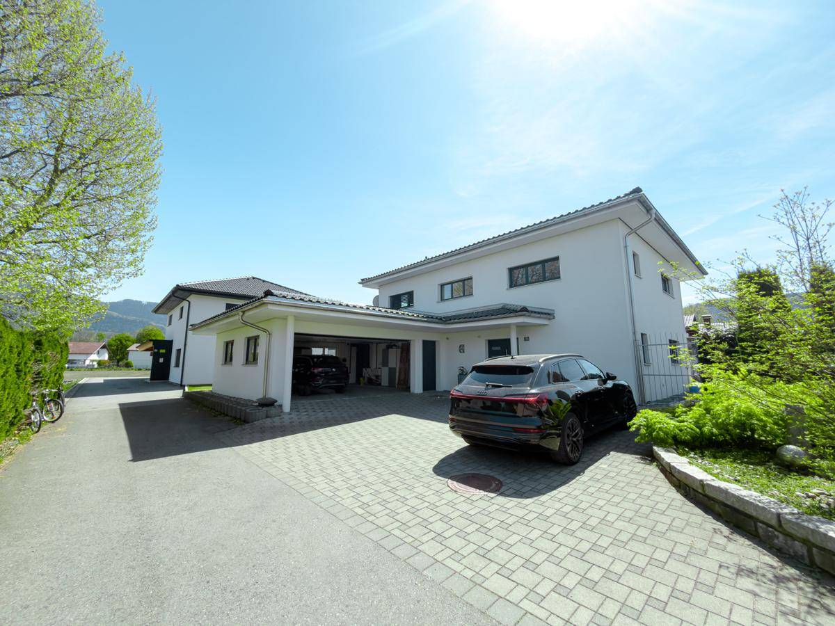 Ansicht des modernen Hauses mit Carport, Auffahrt und gepflegter Außenanlage.