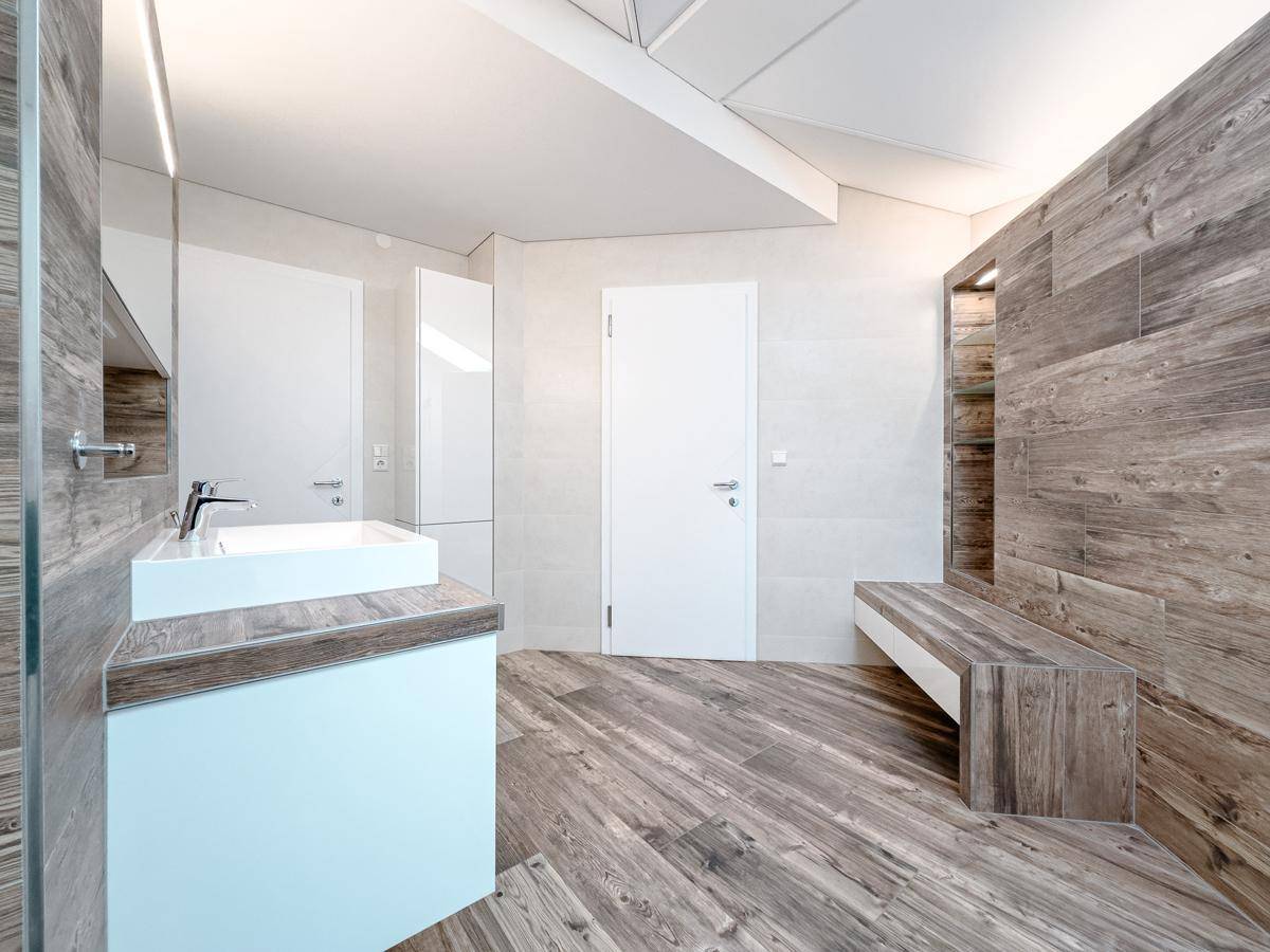 Modernes Badezimmer mit Holzoptikfliesen, Doppelwaschbecken und stilvoller Einrichtung.