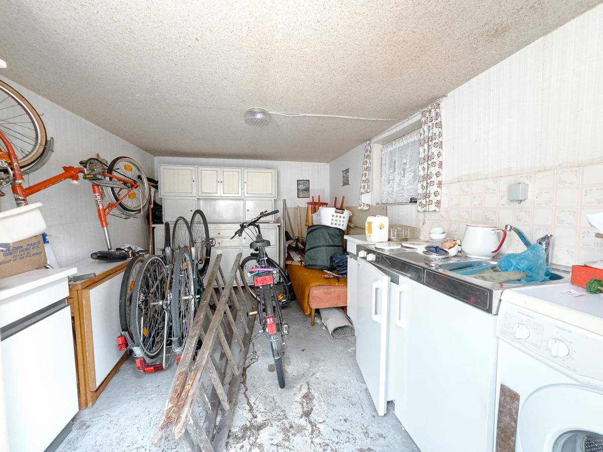 Praktischer Hauswirtschaftsraum mit Waschmaschine, Spülbecken und Stauraum für Fahrräder.