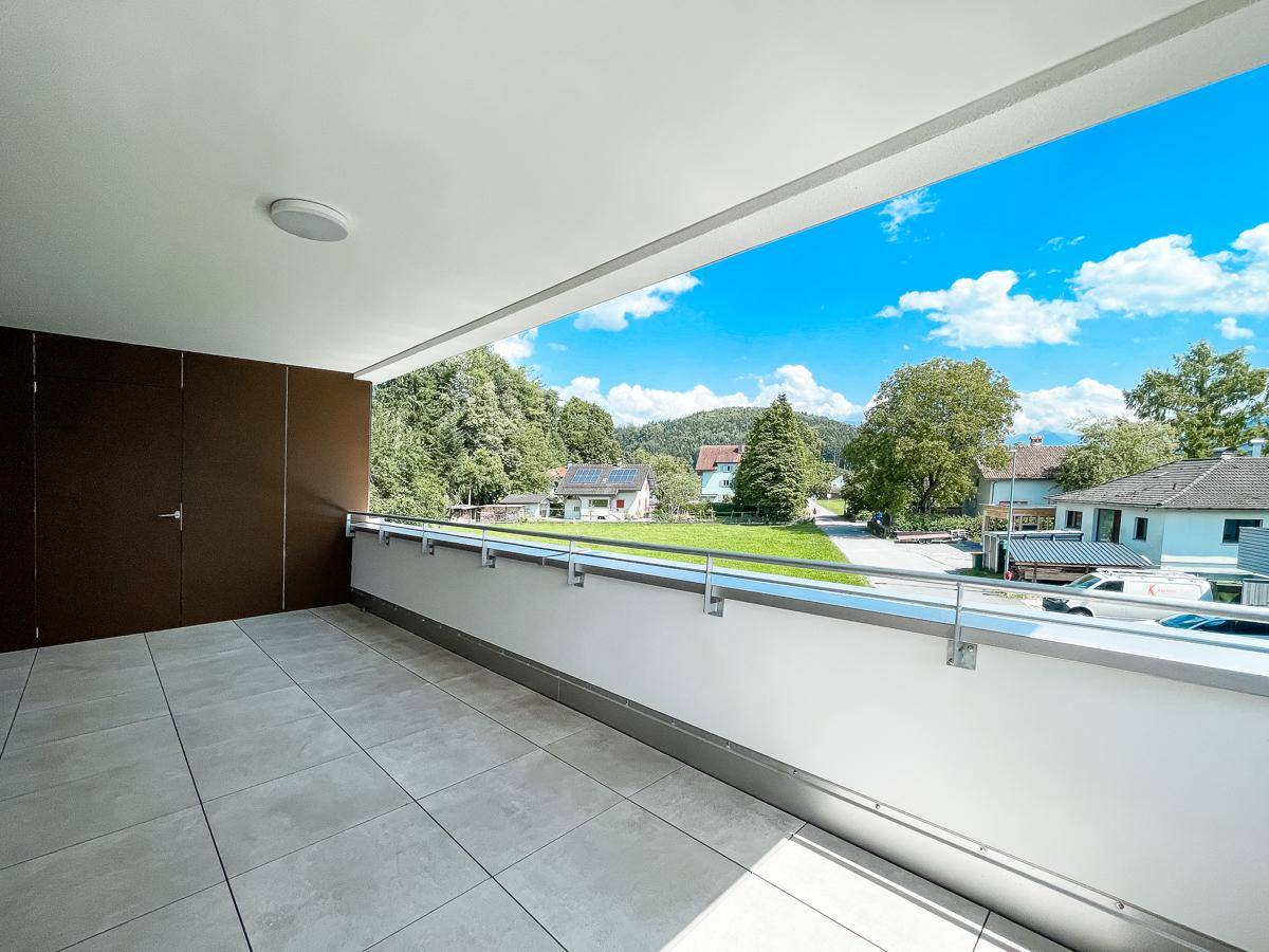 Geräumiger Balkon mit Fliesenboden und weitem Blick über die umliegende Landschaft und Häuser.