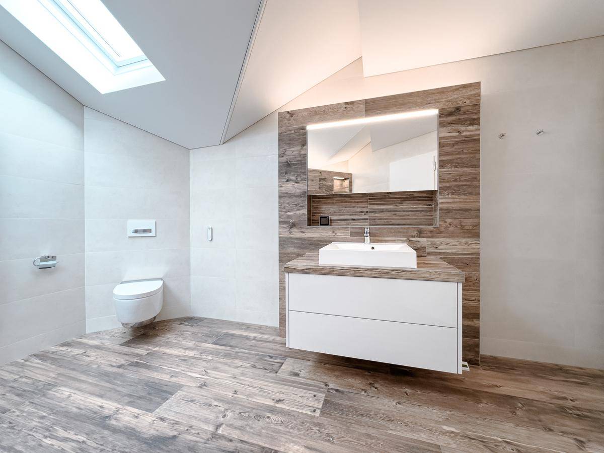 Elegantes Badezimmer mit schwebendem Waschtisch, Wand-WC und Dachfenster für natürliches Licht.