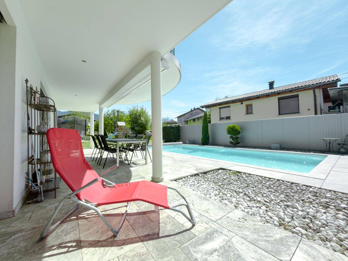 Entspannungsbereich auf der Terrasse mit Liegestuhl und Pool, ideal für sonnige Tage.
