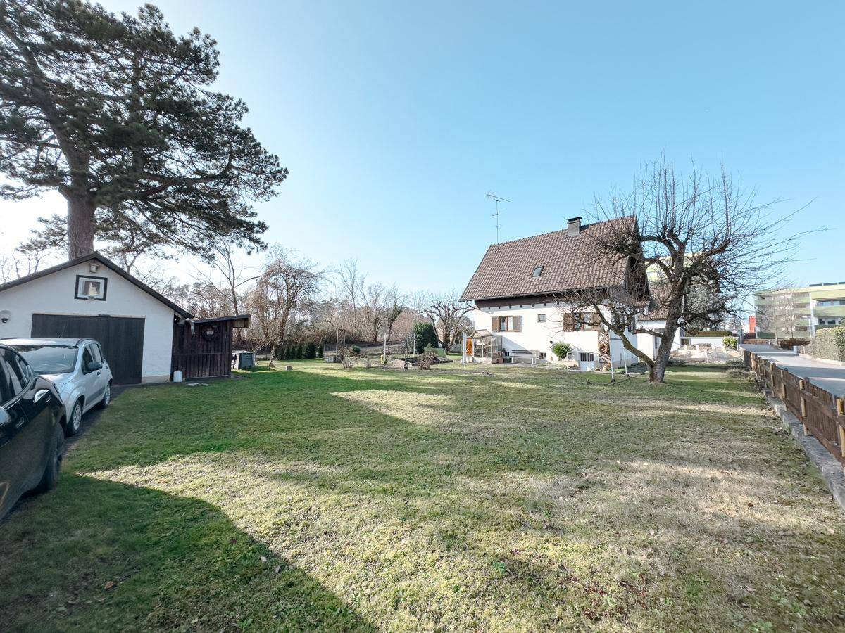 Weitläufiger Gartenbereich mit Einfamilienhaus, Nebengebäude und altem Baumbestand.