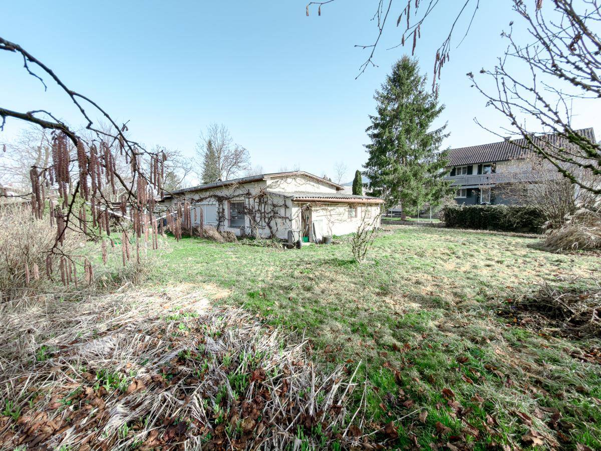 Ansicht des Nebengebäudes auf dem Grundstück mit einem Wohnhaus im Hintergrund.