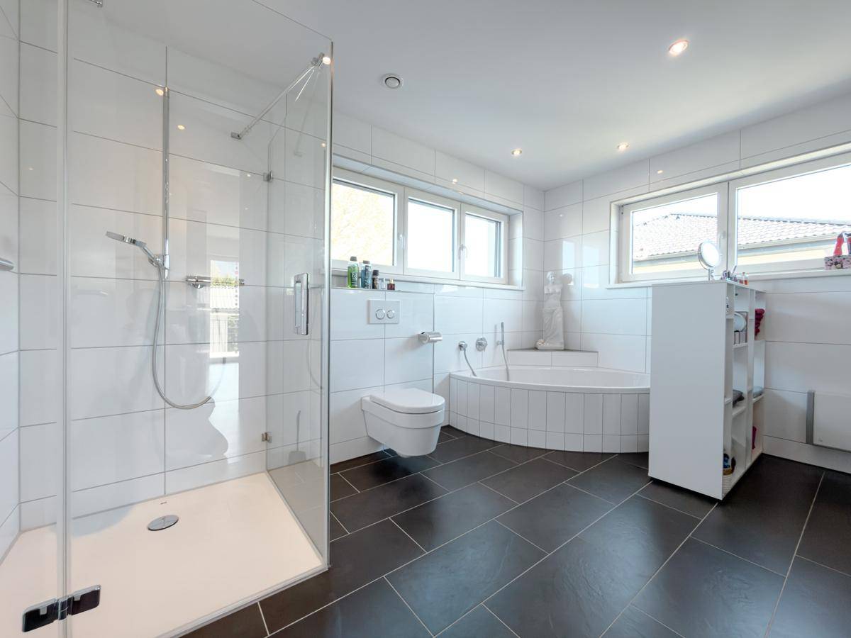 Geräumiges Badezimmer mit großer Dusche, Badewanne und wandmontierter Toilette.