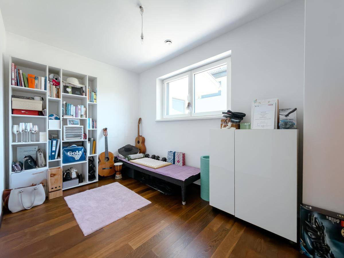 Vielseitiges Zimmer mit Tagesbett, Bücherregal und Holzboden, ideal als Gäste- oder Hobbyraum.