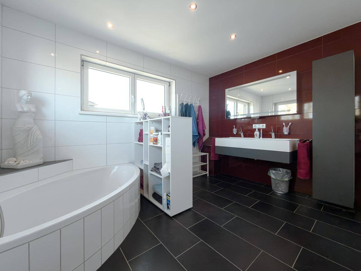 Modernes Badezimmer mit Doppelwaschbecken, Badewanne und großen Fliesen.
