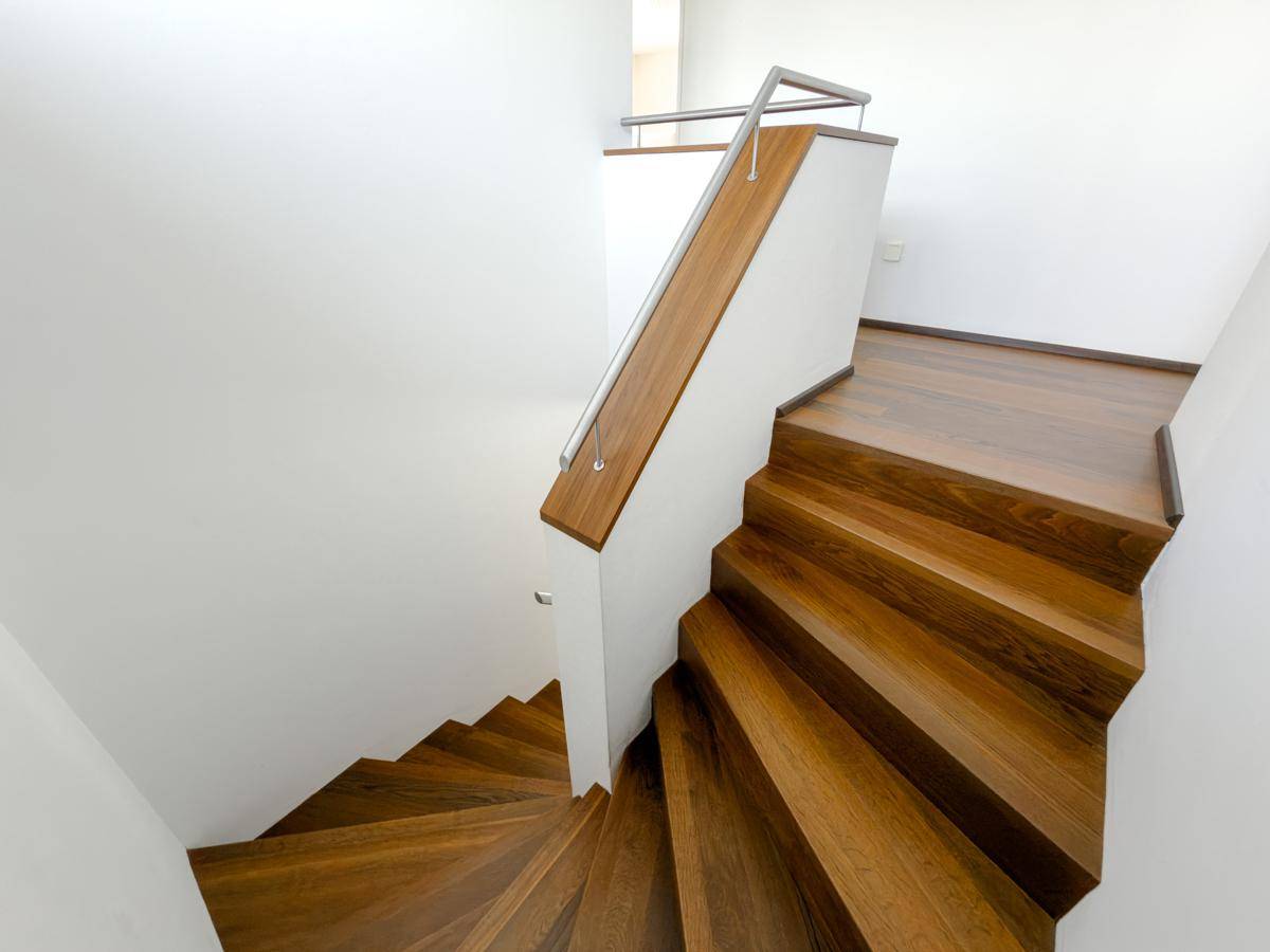 Elegante Holztreppe mit modernem Geländer, die die verschiedenen Etagen verbindet.