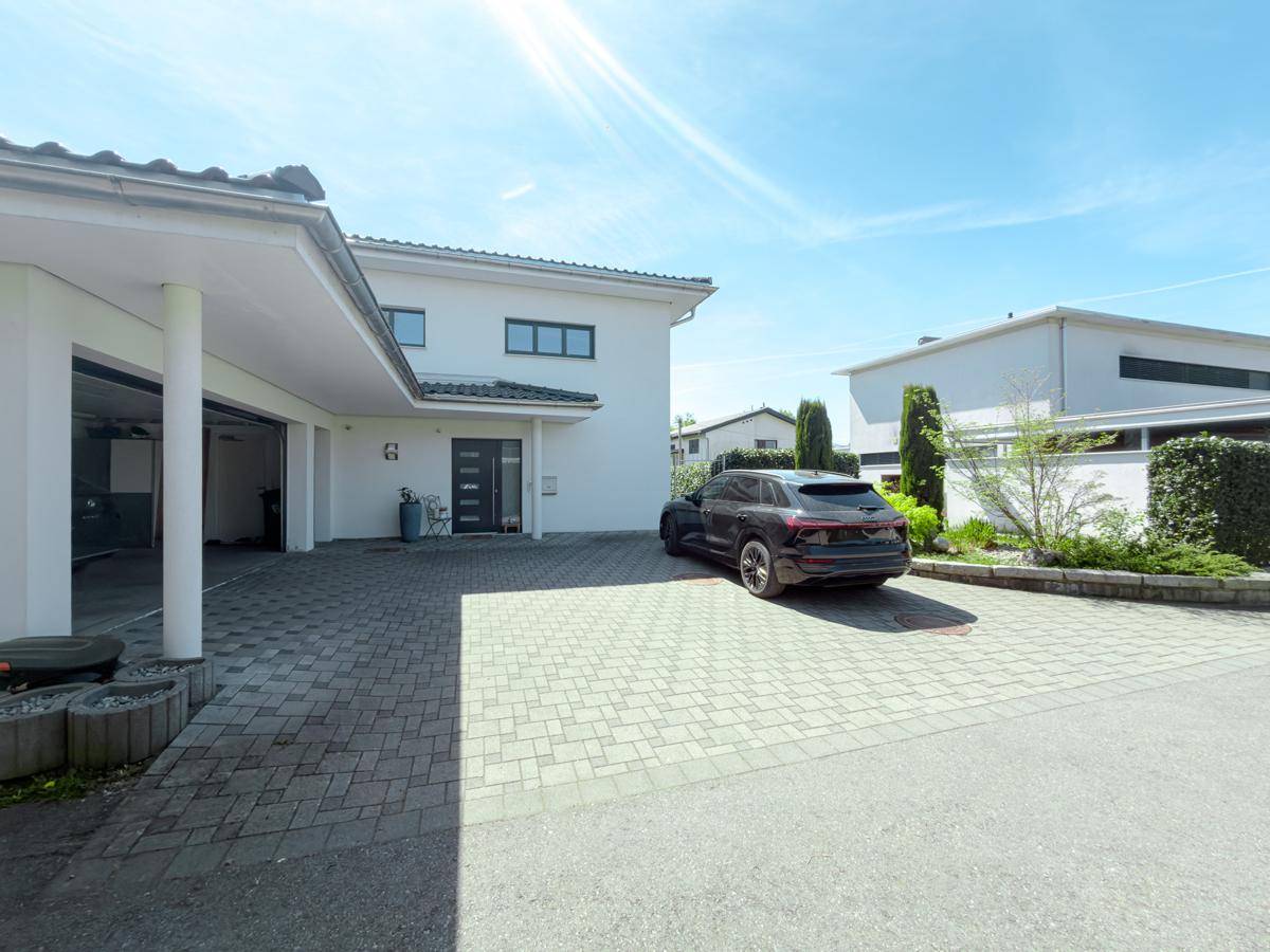 Geräumige Auffahrt mit Carport und Eingangsbereich des modernen Einfamilienhauses.