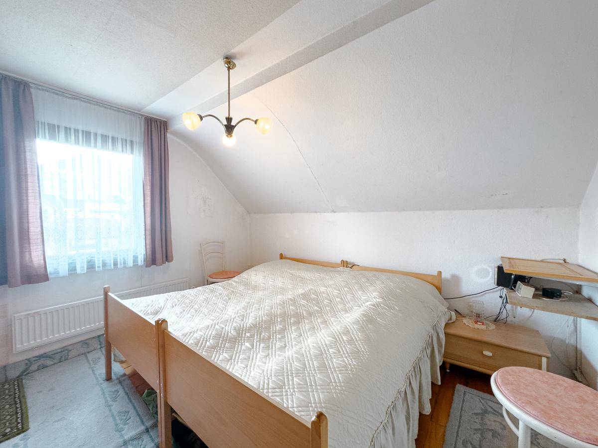 Helles Schlafzimmer im Dachgeschoss mit Doppelbett und Fenster, bietet eine gemütliche Atmosphäre.