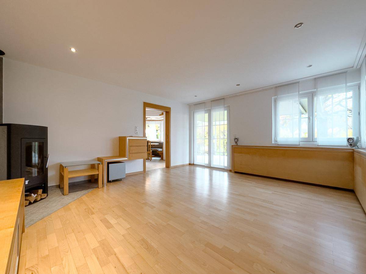 Helles Wohnzimmer mit Parkettboden, Kaminofen und Zugang zur Terrasse.