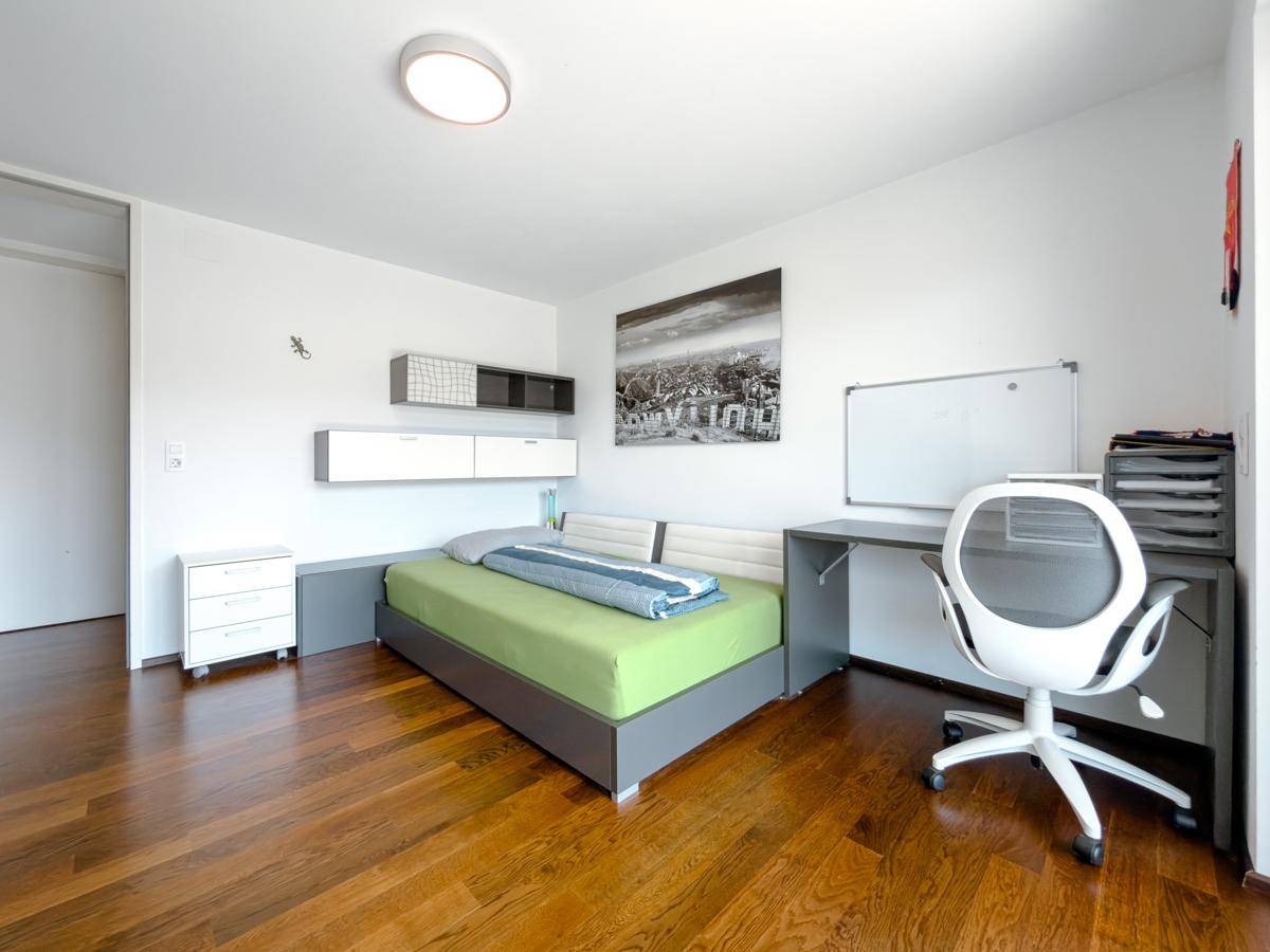 Modern eingerichtetes Schlafzimmer mit Bett, Schreibtisch und Stauraum, ideal für Jugendliche.
