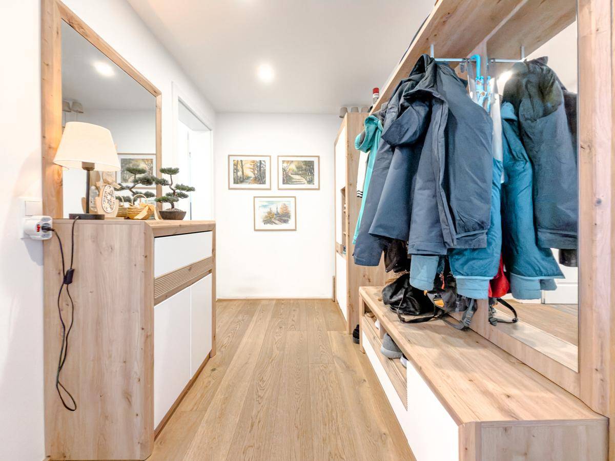 Funktionaler Flur mit Garderobe, Spiegel und Holzboden, bietet viel Stauraum.