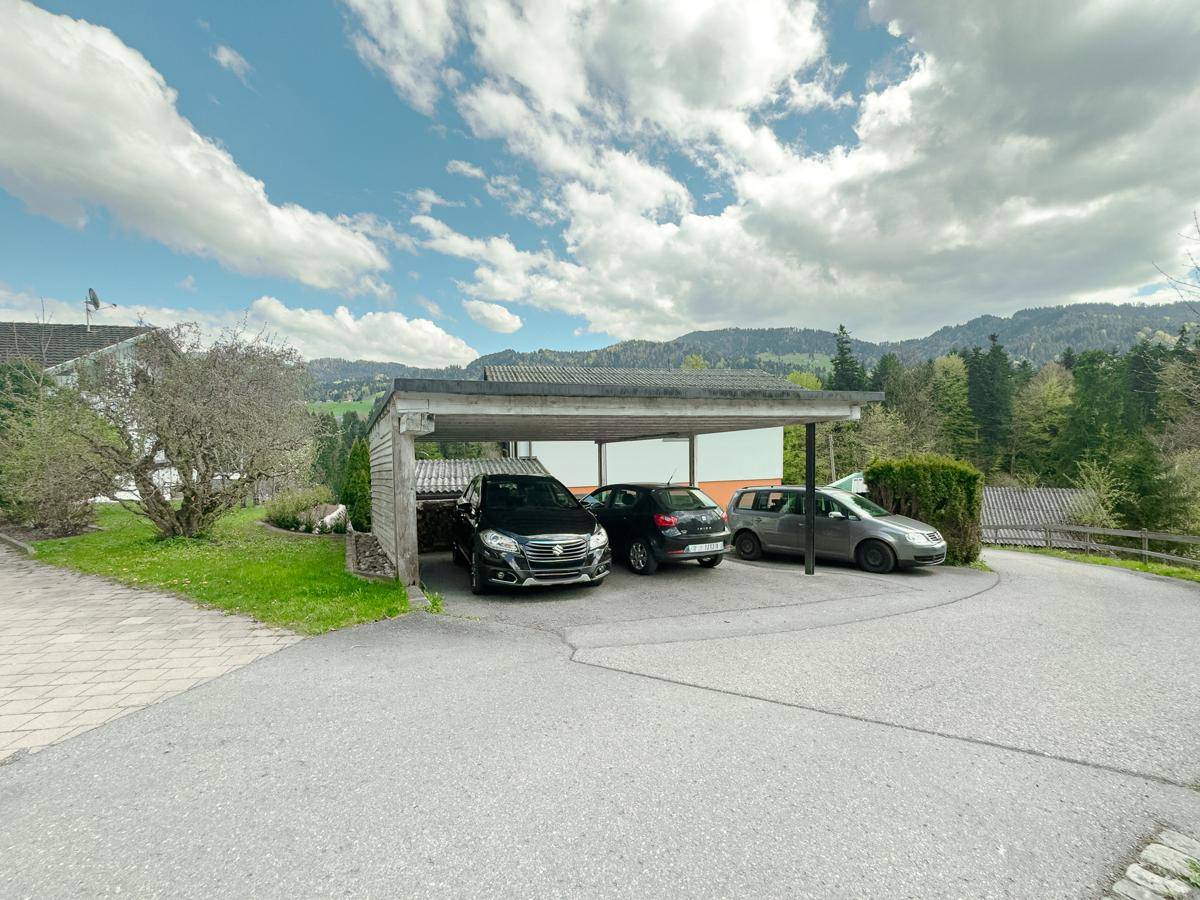 Überdachter Carport mit mehreren Stellplätzen und Blick auf die umliegende Berglandschaft.