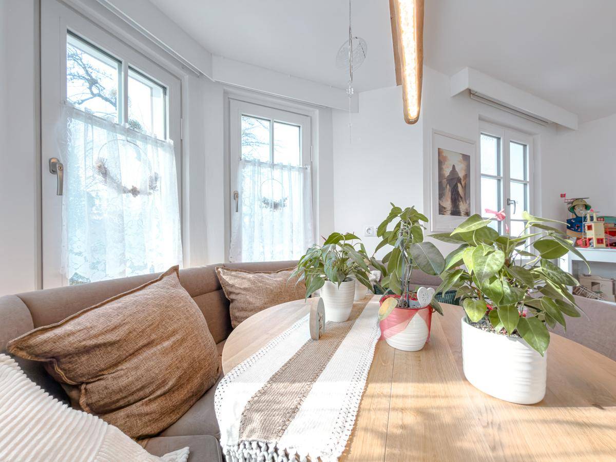 Gemütlicher Essbereich mit Holztisch, Eckbank und Pflanzen, die eine wohnliche Atmosphäre schaffen.