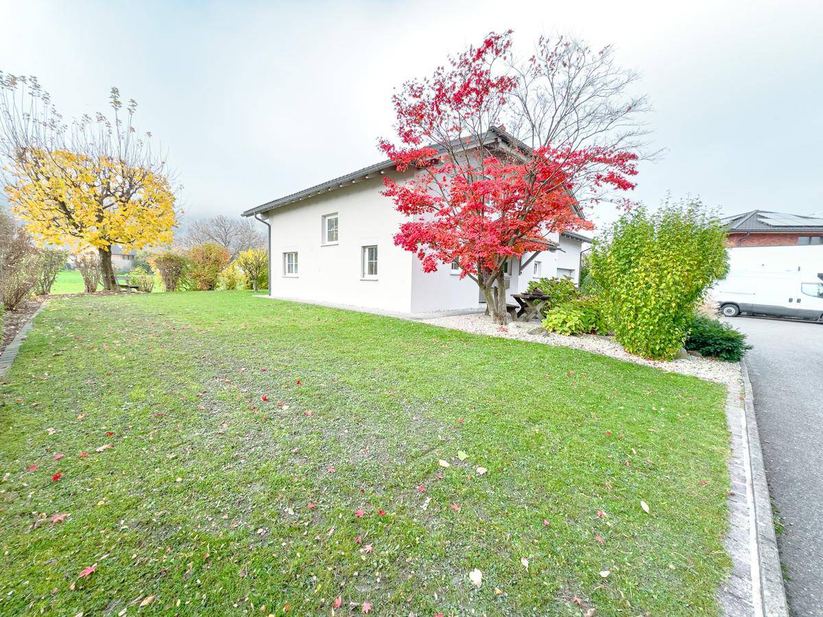 Große Rasenfläche neben dem Haus mit bunten Herbstbäumen und Blick in die Umgebung.