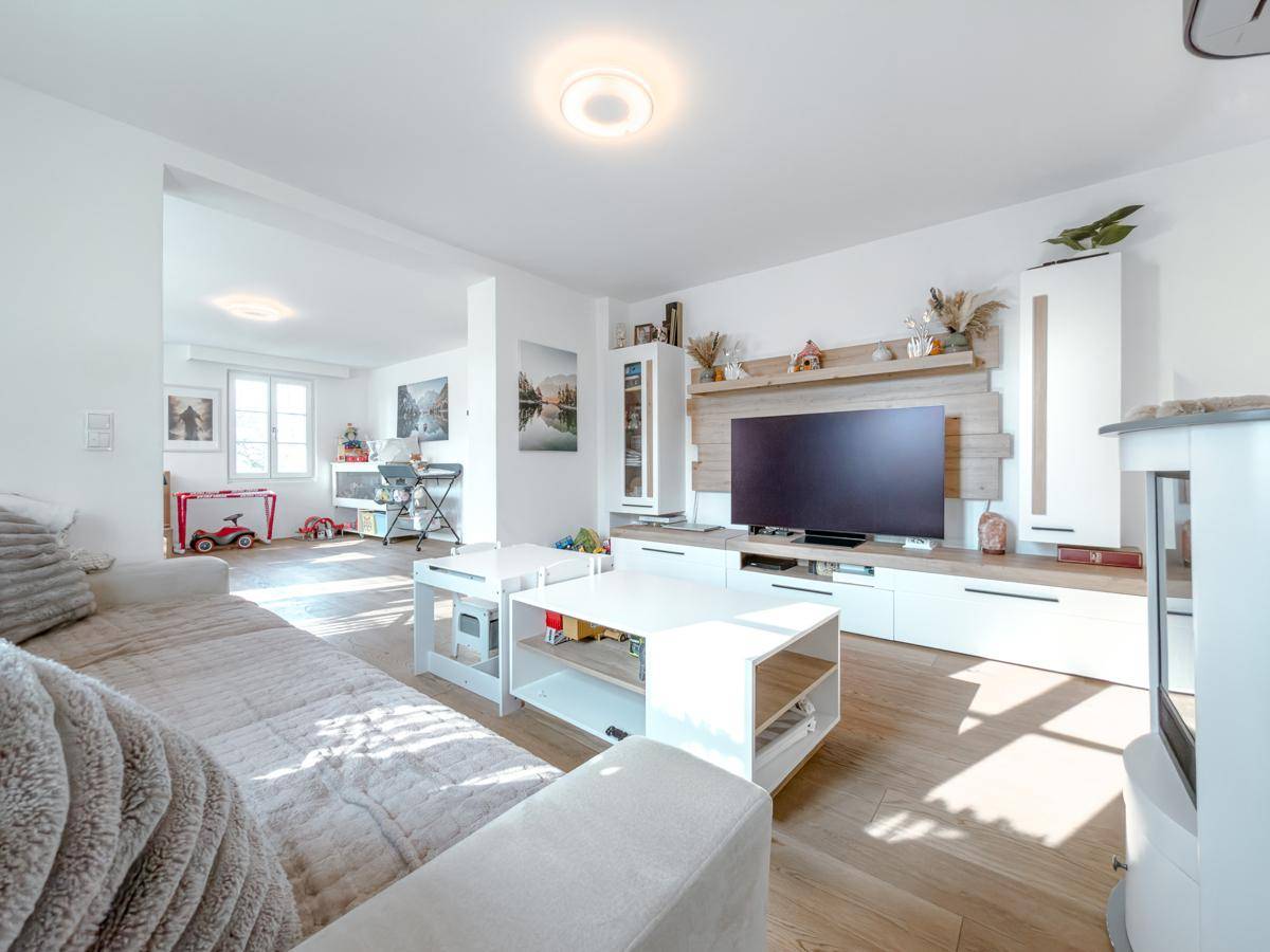 Modernes Wohnzimmer mit hellem Sofa, TV-Möbeln und Holzboden, offen gestaltet.