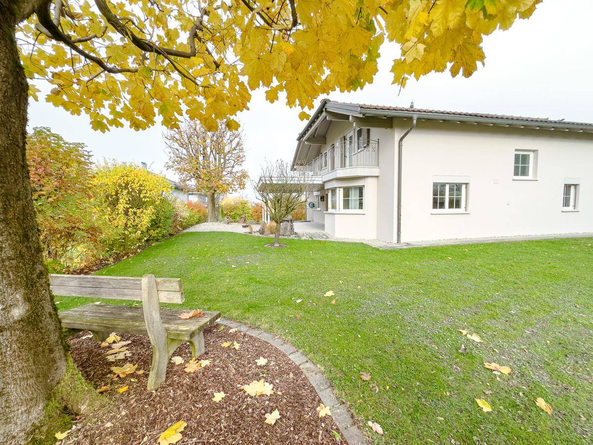Großzügiger Garten mit Rasenfläche, Baumbestand und Blick auf das Wohnhaus.