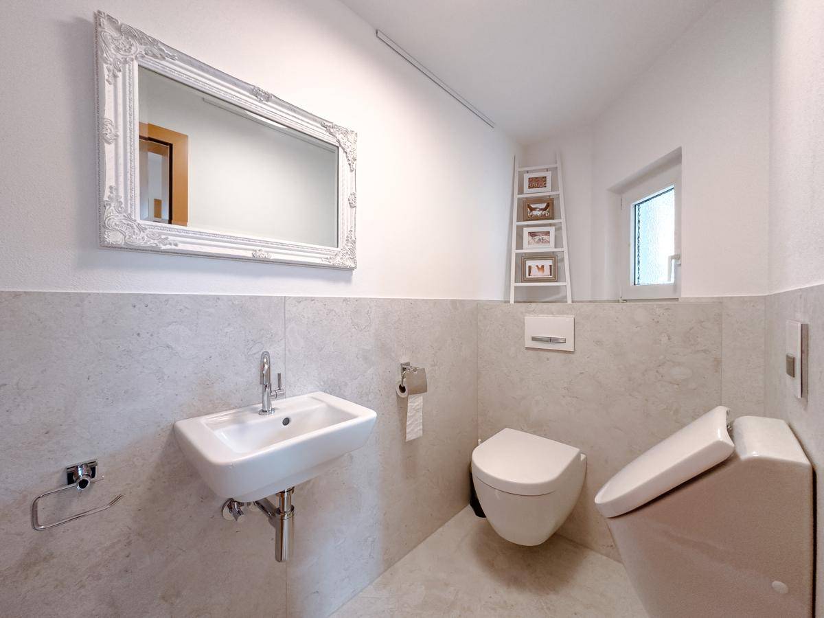 Modernes Gäste-WC mit Wand-WC, kleinem Waschbecken und Fenster.
