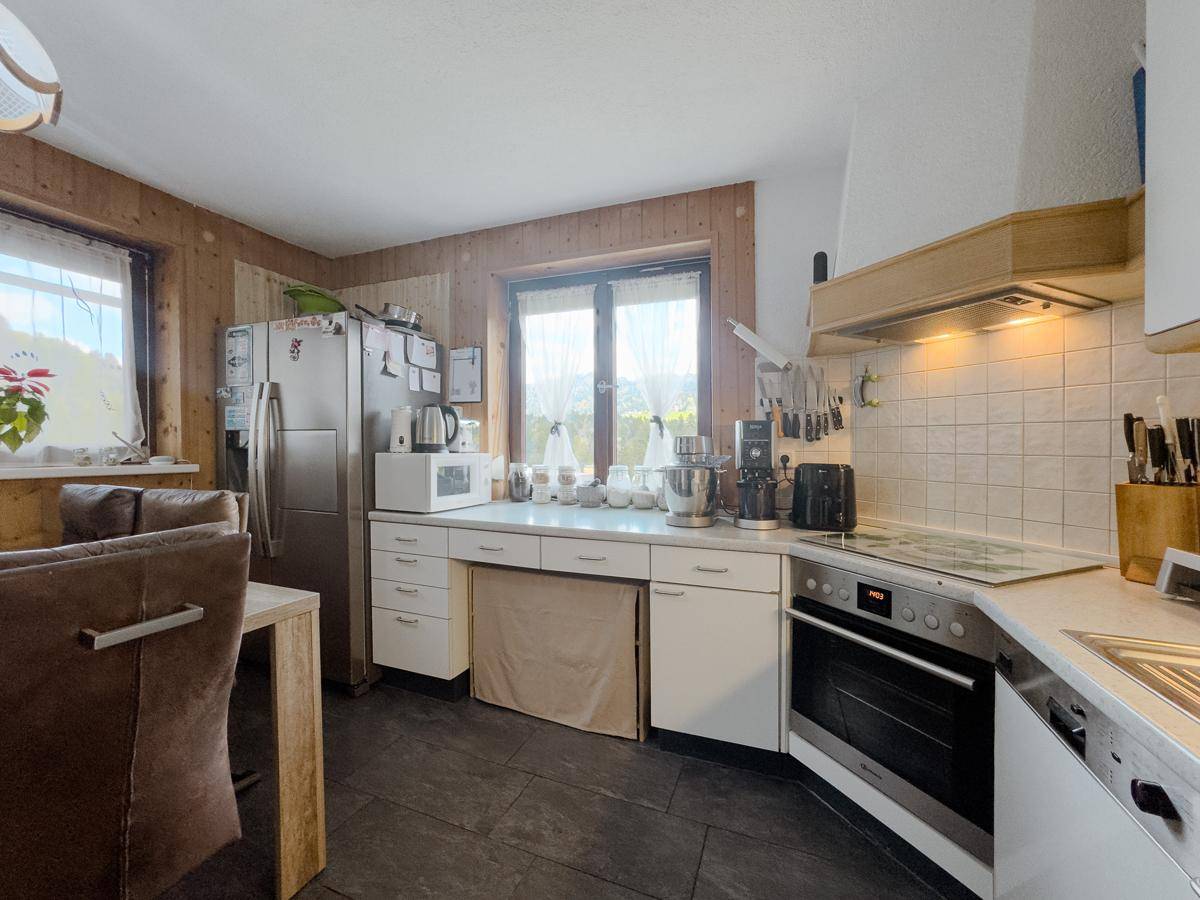 Funktionale Küche mit Kühlschrank, viel Arbeitsfläche und Fenster für natürliches Licht.