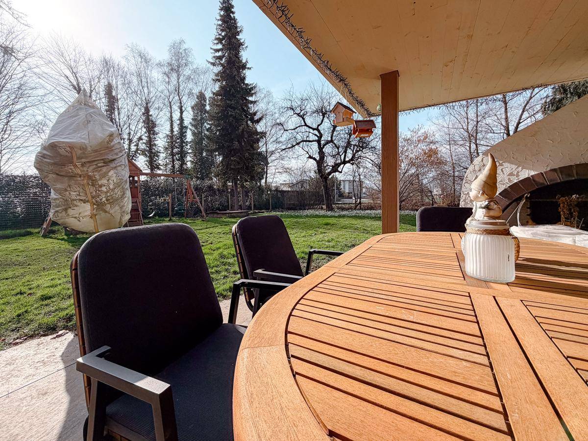 Detailansicht des Esstisches auf der überdachten Terrasse mit Blick in den grünen Garten.