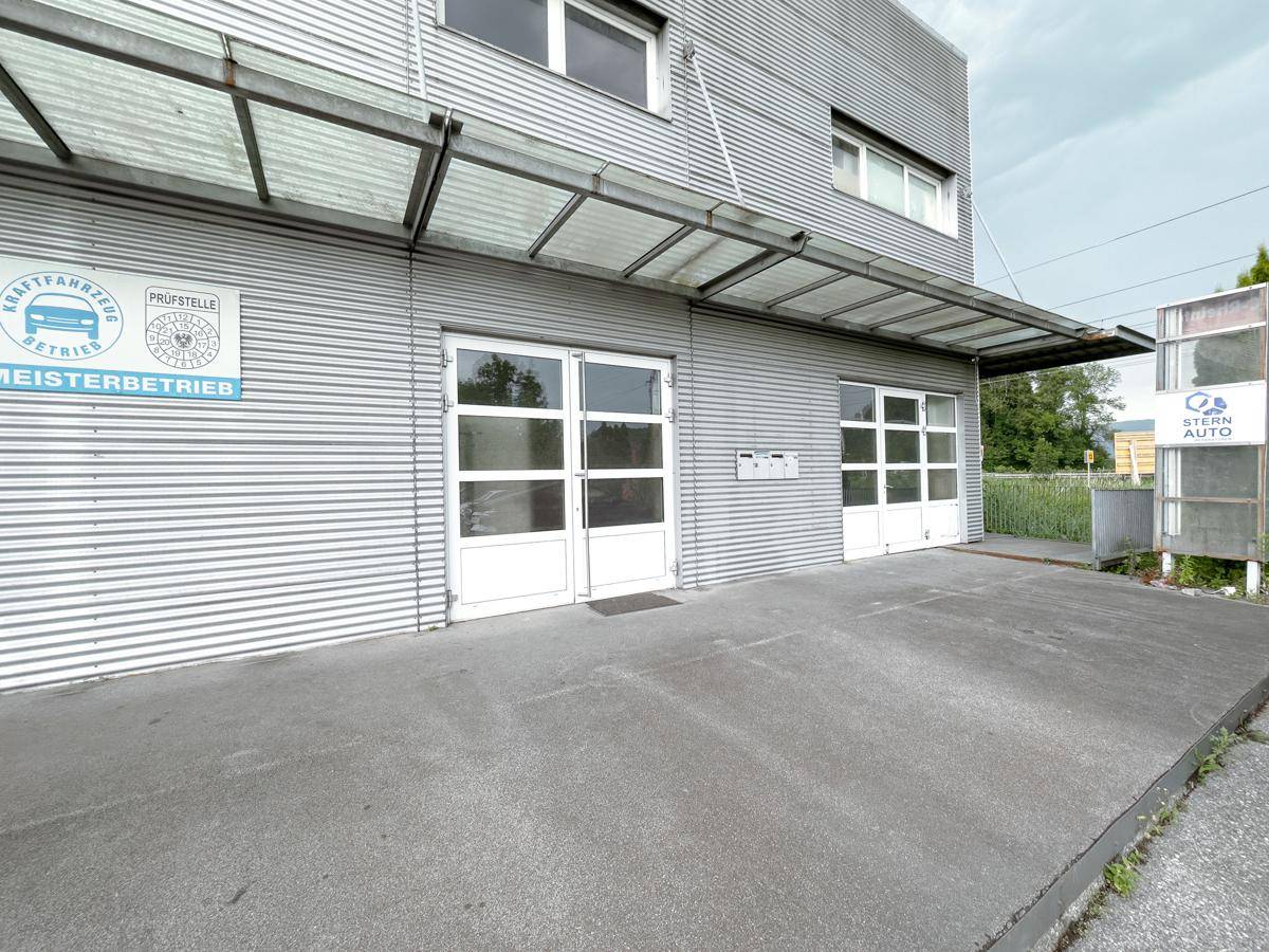 Nahaufnahme der Gebäudefassade mit zwei Garagentoren und einem Vordach, das den Eingangsbereich schützt.