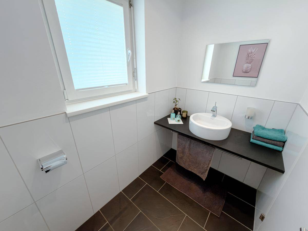 Modernes Gäste-WC mit Fenster, dunklen Fliesen und minimalistischem Waschbecken.