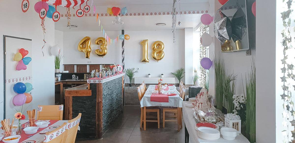 Festlich dekorierter Essbereich mit Ballons und Girlanden, bereit für eine Feier mit Buffet und Tischen.