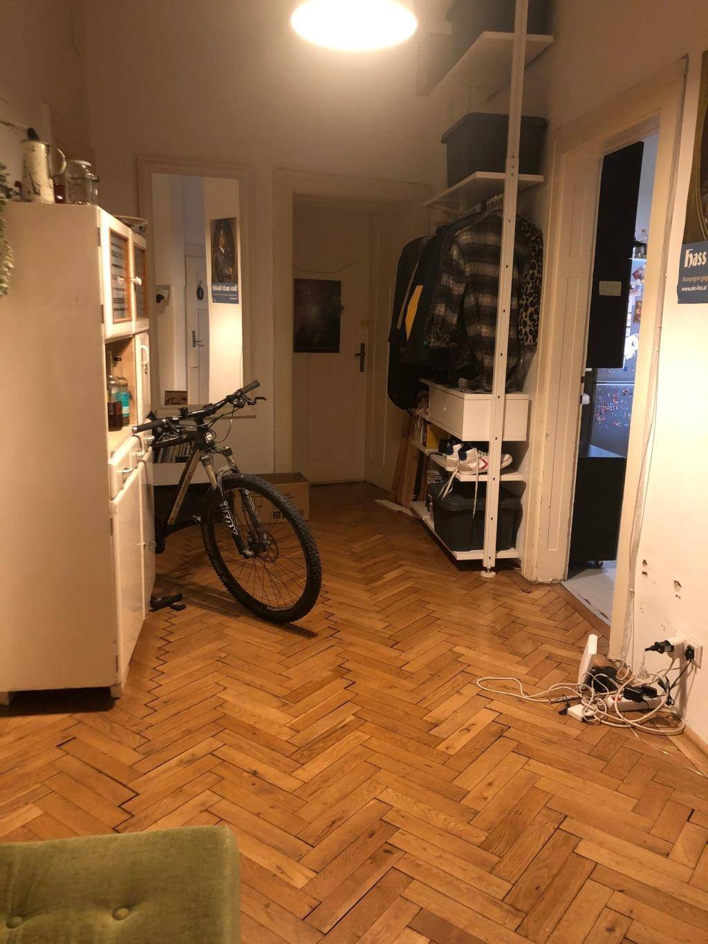 Geräumiger Flur mit Fischgrätparkett, praktischen Regalen und Abstellmöglichkeiten, inklusive Fahrrad.