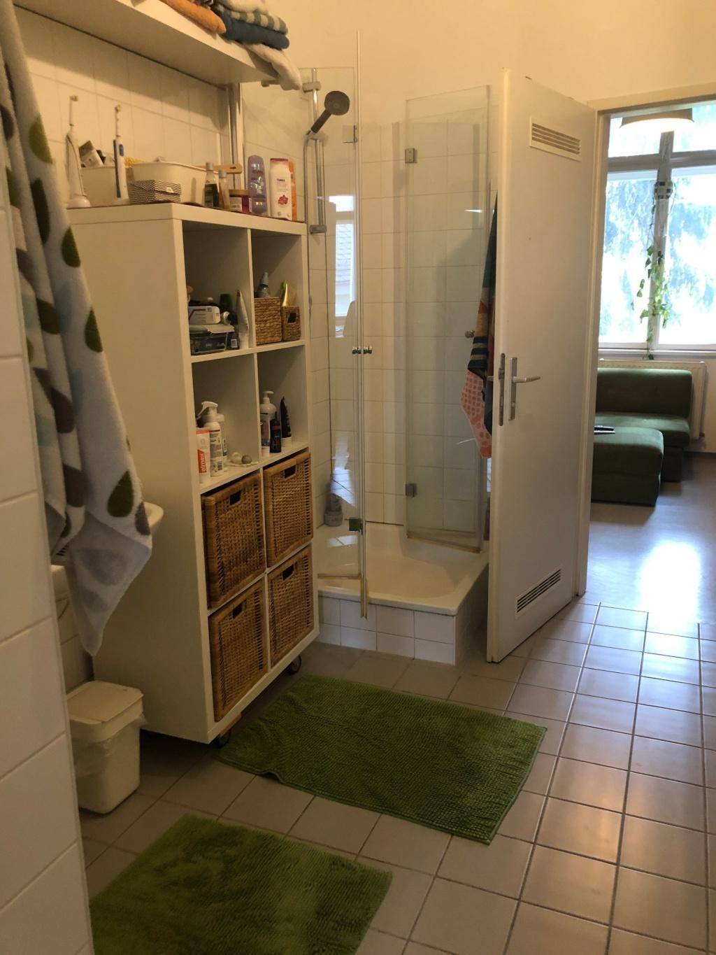 Badezimmer mit Duschkabine, praktischen Regalen und einem Fenster für ausreichend Tageslicht.