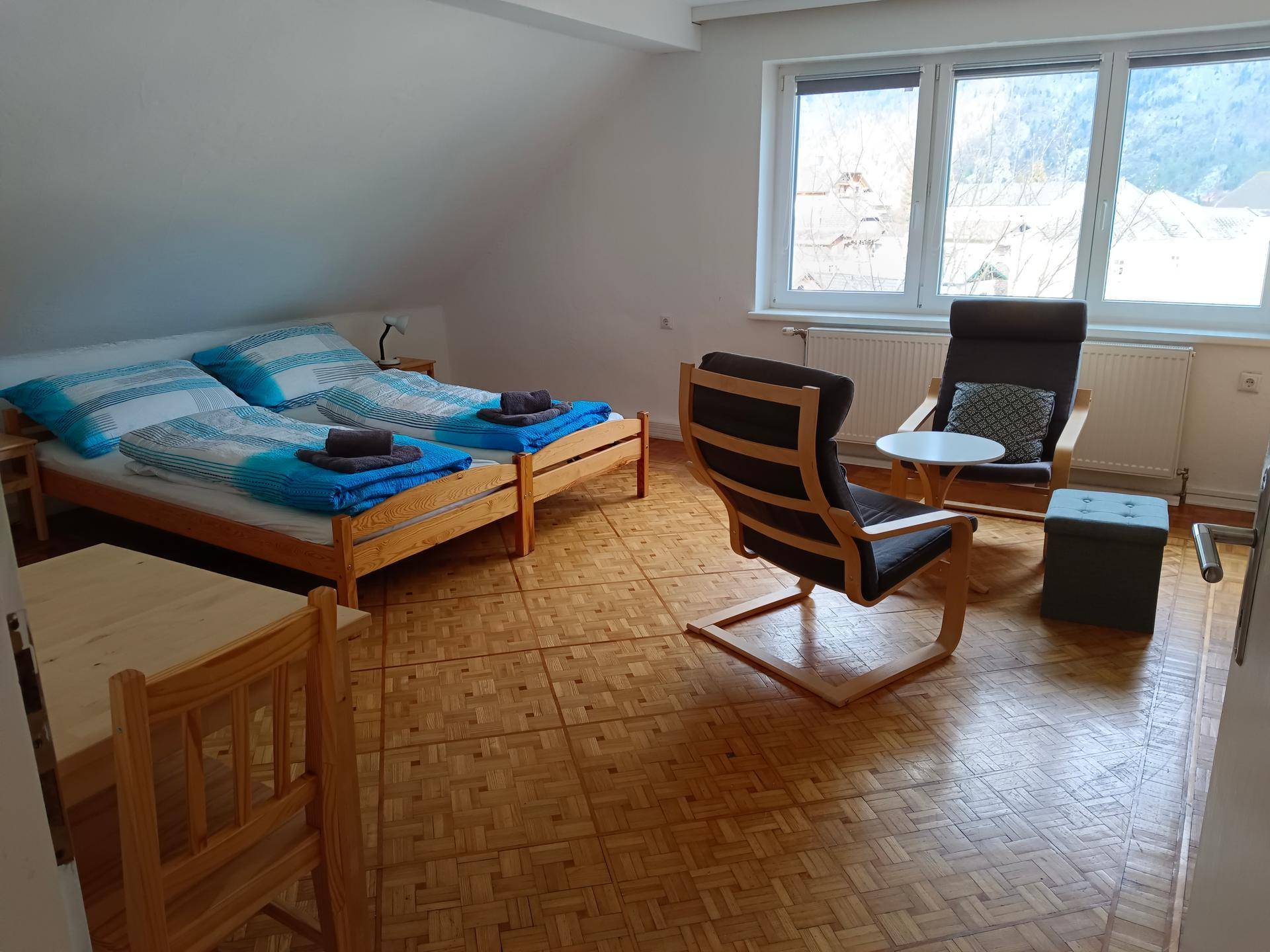 Helles Schlafzimmer mit zwei Einzelbetten, bequemen Sesseln und Parkettboden.