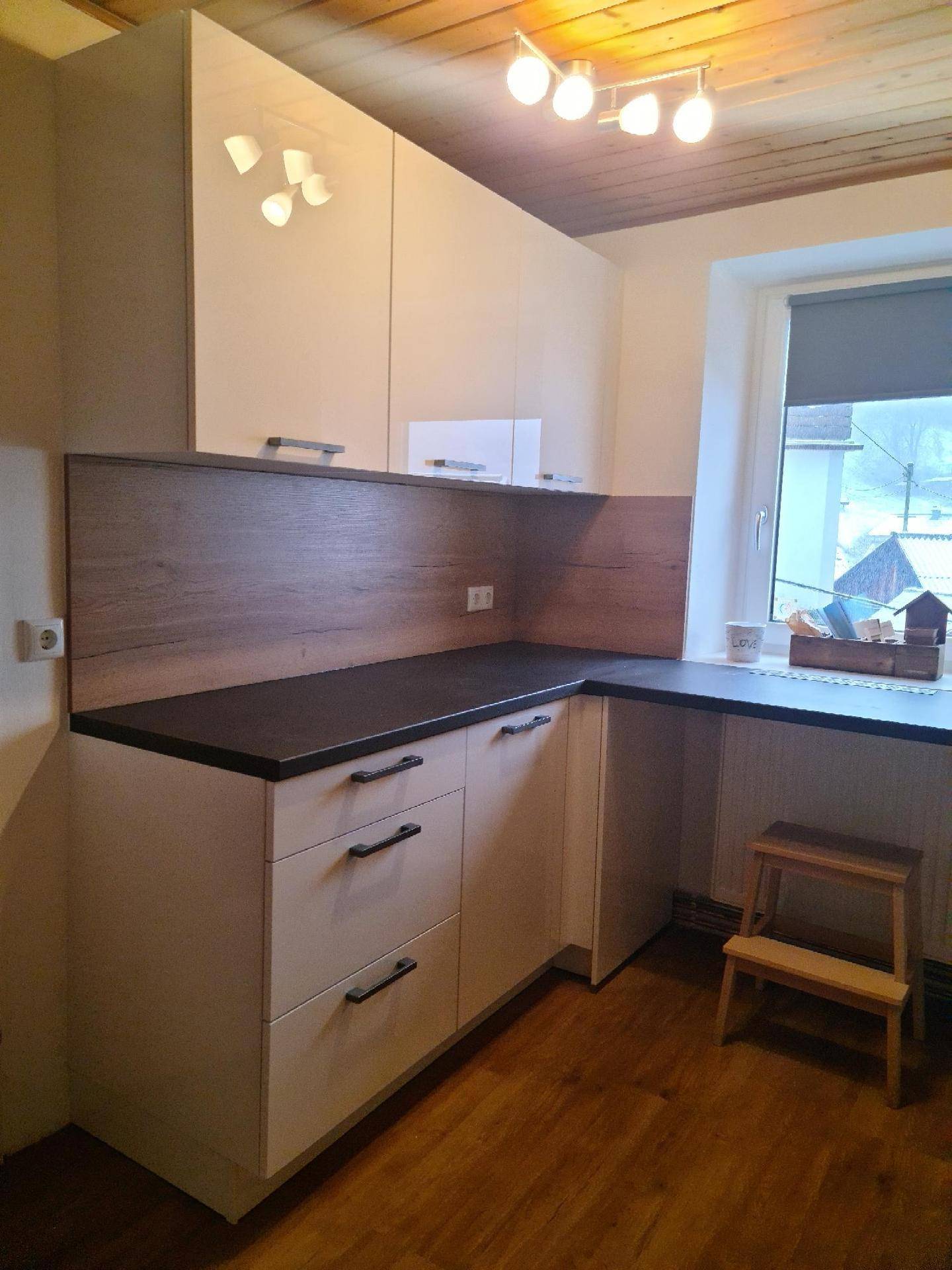 Funktionale Küche mit weißen Schränken, Holz-Arbeitsplatte und einem Fenster.