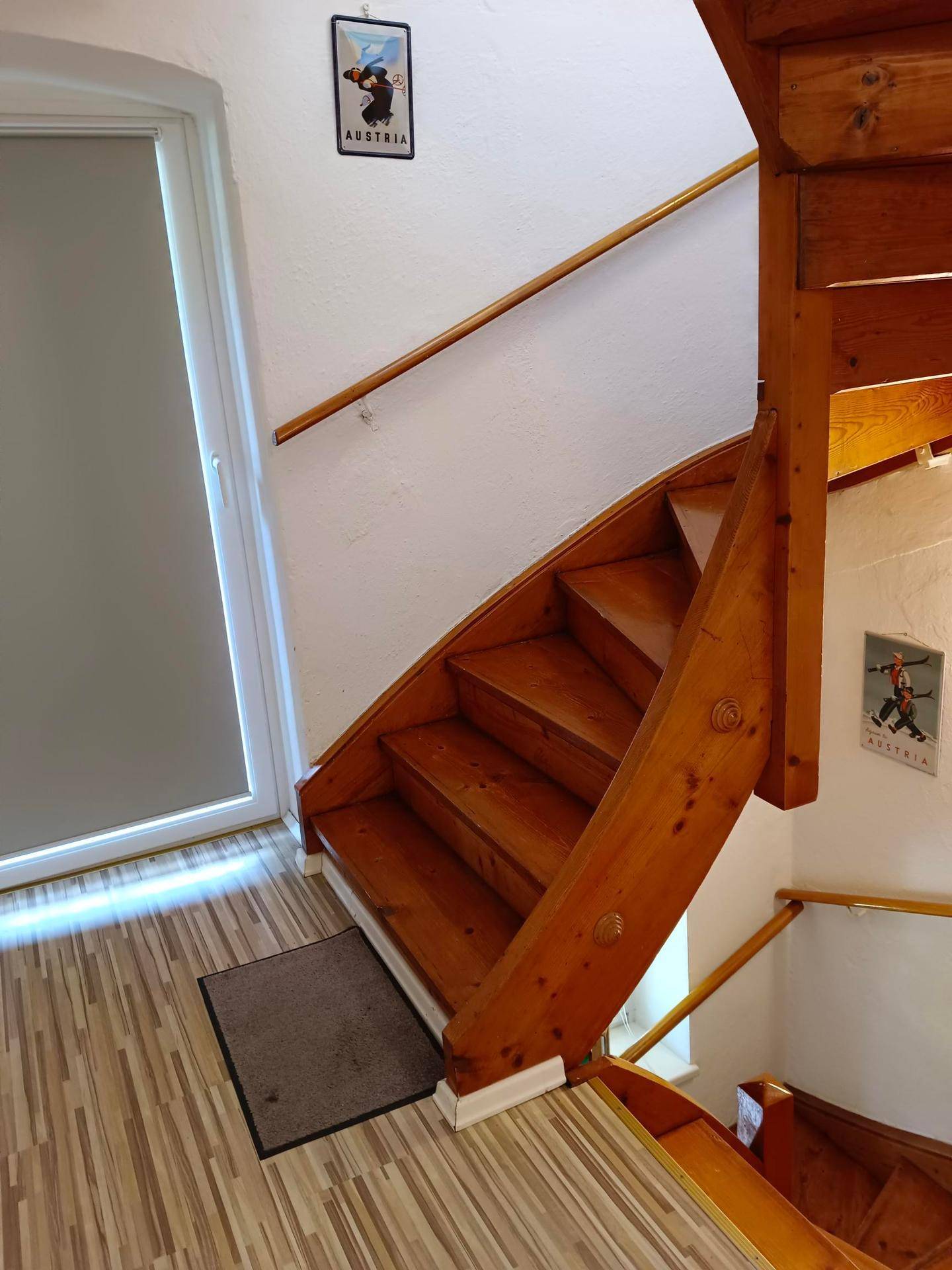 Rustikale Holztreppe führt in die obere Etage, mit Laminatboden im Eingangsbereich.