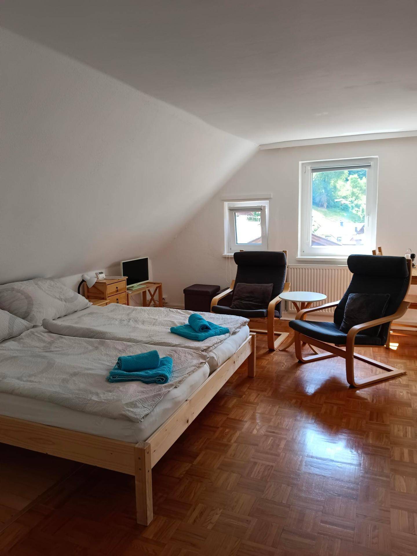 Gemütliches Schlafzimmer mit zwei Betten, Sitzgelegenheiten und Dachschrägen.
