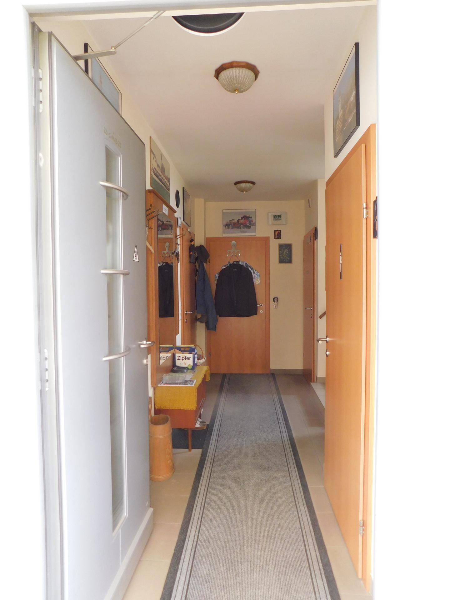 Heller Flur mit Fliesenboden, Garderobe und mehreren Türen, die zu anderen Räumen führen.