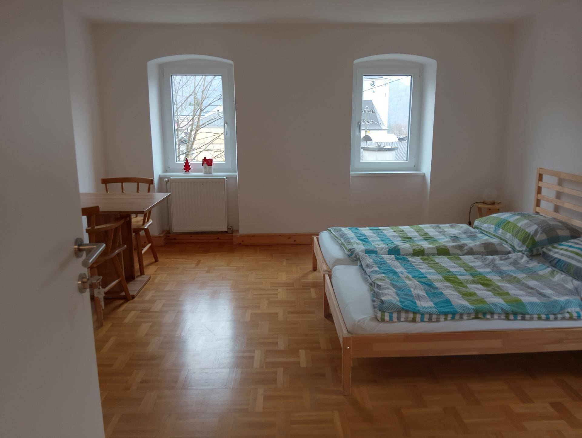 Geräumiges Schlafzimmer mit zwei Einzelbetten, Esstisch und Parkettboden.