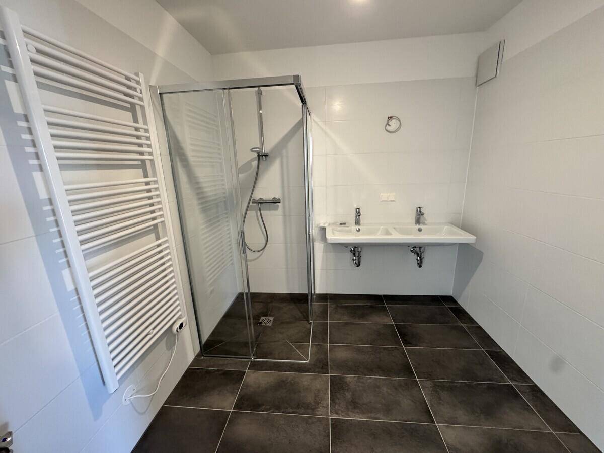 Modernes Badezimmer mit ebenerdiger Dusche, Doppelwaschbecken und beheiztem Handtuchhalter.