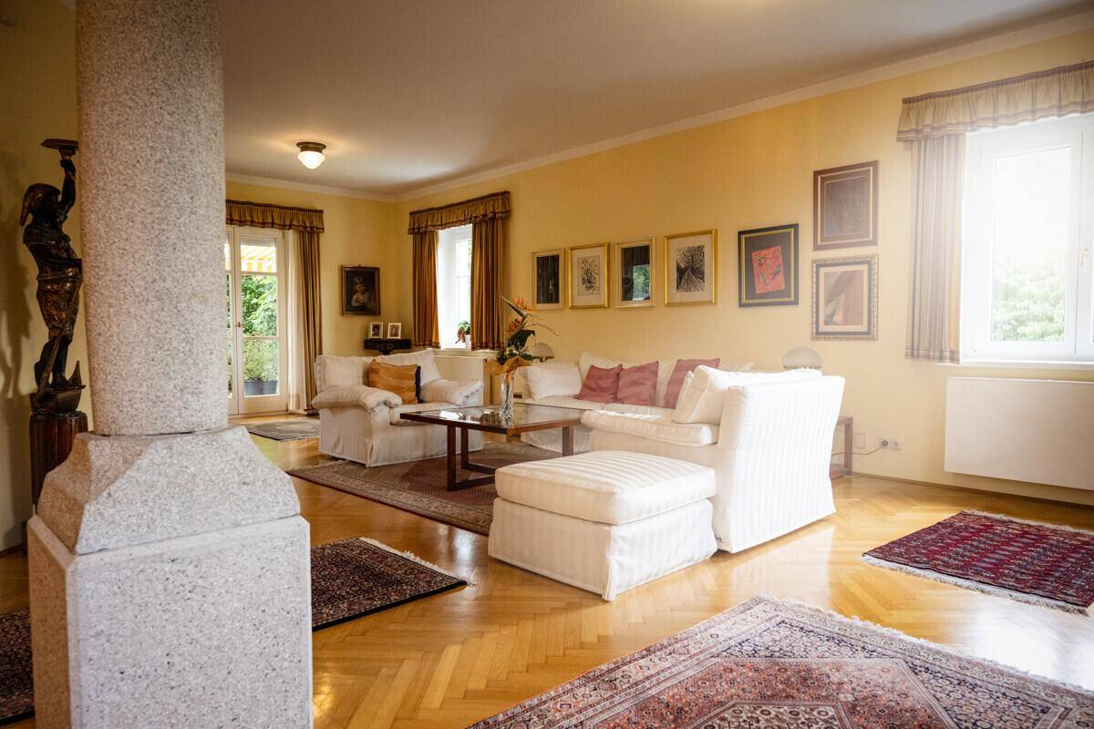 Helles Wohnzimmer mit Parkettboden, bequemen weißen Sofas und Zugang zur Terrasse.
