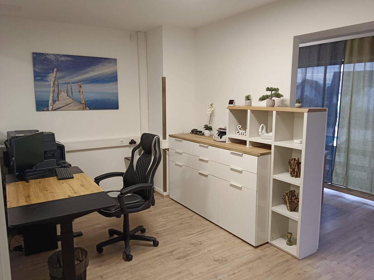 Moderner Bürobereich mit Arbeitsplatz, Stauraum und Laminatboden.