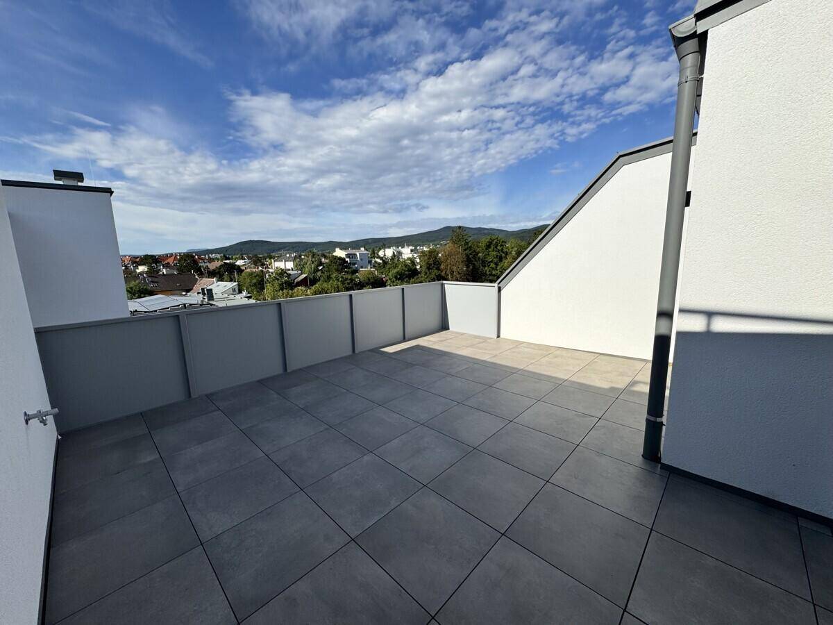 Große, geflieste Dachterrasse mit weitem Blick über die Stadt und die umliegenden Berge.