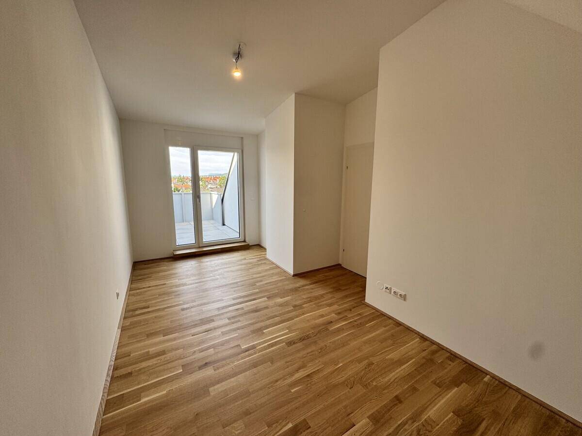 Heller Raum mit Holzboden und Zugang zu einer privaten Terrasse.