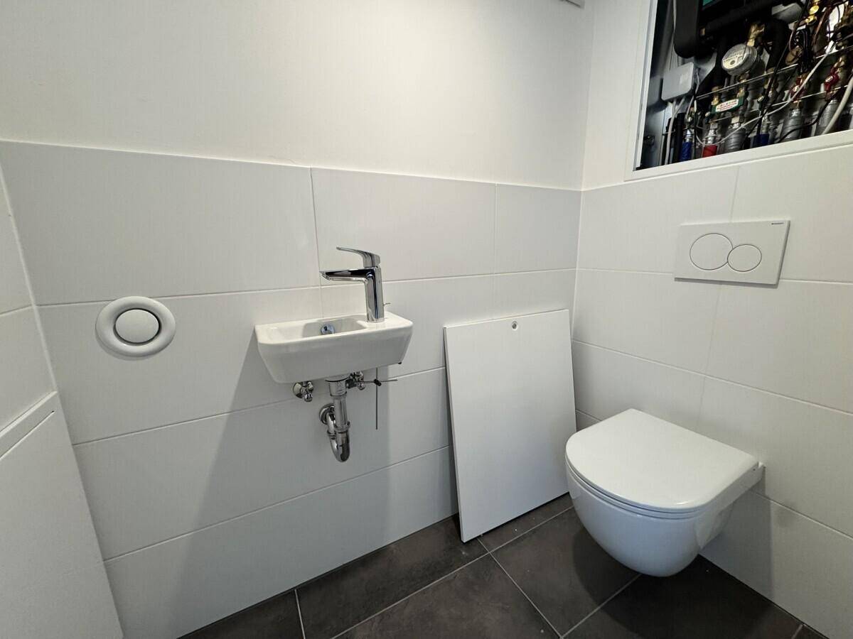 Modernes Gäste-WC mit wandhängender Toilette und kleinem Waschbecken.